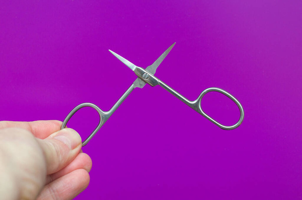 small manicure open scissors in hand on a purple background - Photo, Image