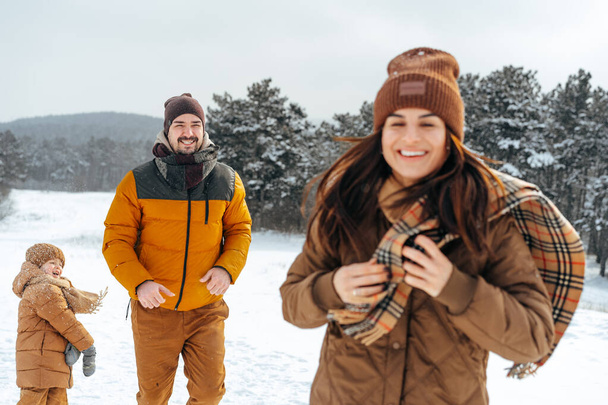 Happy family having a walk in winter outdoors in snow - Foto, afbeelding