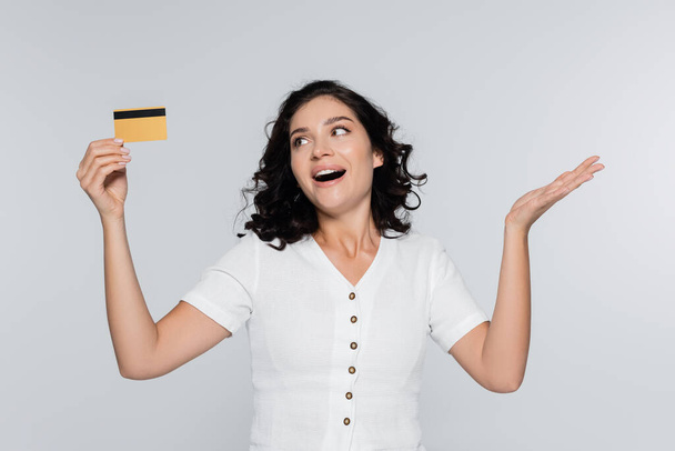 vzrušená mladá žena držící kreditní kartu s cashback izolované na šedé - Fotografie, Obrázek