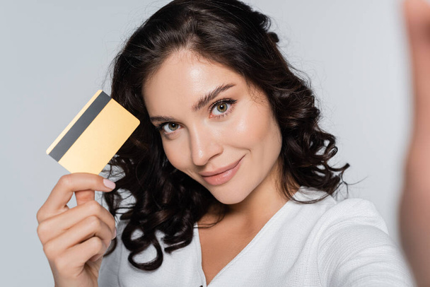 joyeuse jeune femme tenant carte de crédit avec cashback isolé sur gris - Photo, image