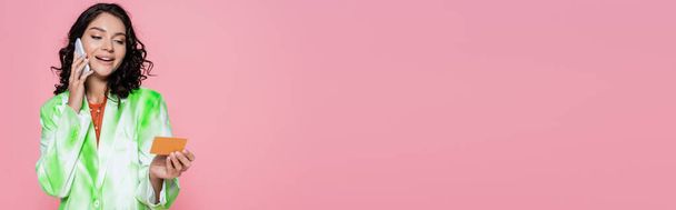 jovem feliz em gravata corante blazer segurando cartão de crédito e falando no smartphone isolado em rosa, banner - Foto, Imagem