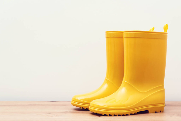 Żółte gumowe buty na drewnianej półce. Żółte buty deszczowe na wiosnę lub jesień deszczową pogodę. Jesienna moda. Zakupy i sprzedaż sezonowa. - Zdjęcie, obraz