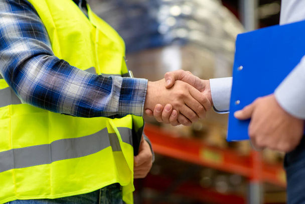 worker and businessman shaking hands at warehouse - Фото, зображення