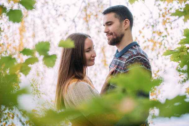 Романтическое свидание, прогулка на природе. Молодая пара влюбленных вместе в лесу в начале осени. Мужчина и женщина прогуливаются по парку в желтой осенней листве - Фото, изображение