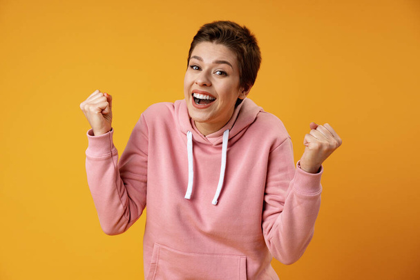 Surprised happy beautiful woman looking in excitement over yellow background - Фото, зображення