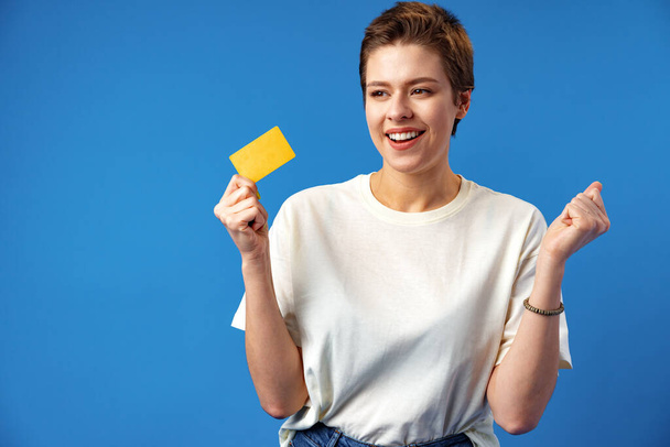 Image of young woman holding business card with copy space on blue background - Фото, зображення