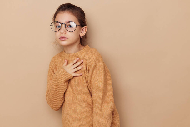 Portrait of happy smiling child girl in a sweater and posing glasses isolated background - Zdjęcie, obraz