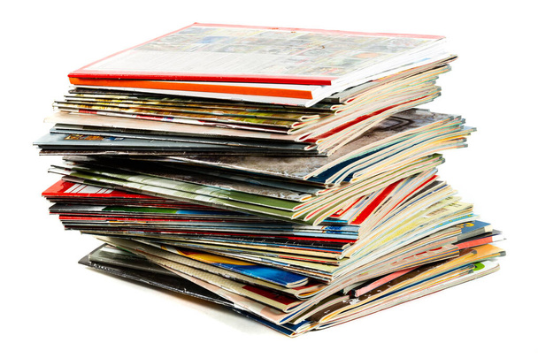 Una pila desordenada de revistas viejas y coloridas sobre fondo claro. - Foto, imagen