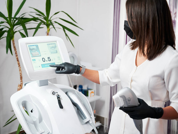 Female cosmetologist using ultrasound SMAS lifting machine. - Photo, Image