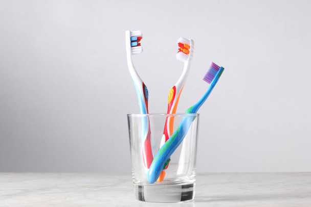 три зубные щетки для родителей и ребенка в стакане с копировальным местом для текста - Фото, изображение