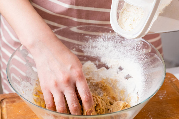 Cierre de las manos de la mujer panadero amasar la masa y añadir la harina en el tazón de la mezcla. Pastelería casera para pasteles o galletas - Foto, imagen