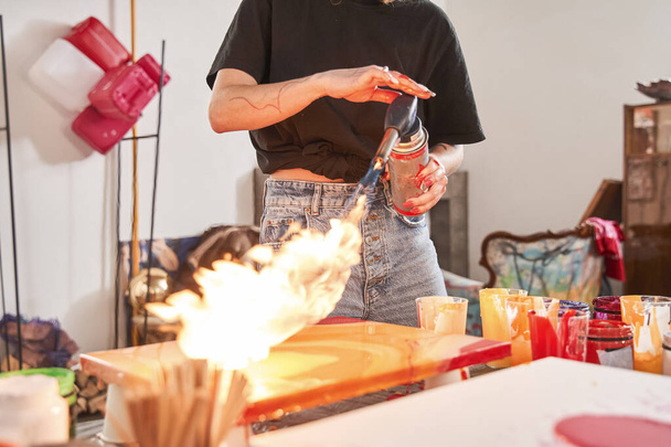 Female painter drying her masterpiece with fire using gas-burner while drawing - Foto, Imagem