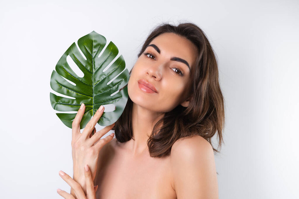 Close-up beauty portret van een topless vrouw met een perfecte huid en natuurlijke make-up, met monstera palmblad - Foto, afbeelding