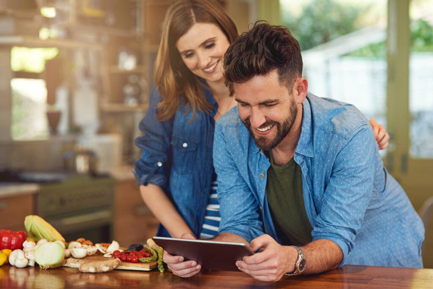 Lataaminen terveellisen aterian suunnitelma yrittää kuin pari. Kuvattu onnellinen nuori pari digitaalisen tabletin avulla valmistettaessa terveellistä ateriaa yhdessä kotona. - Valokuva, kuva