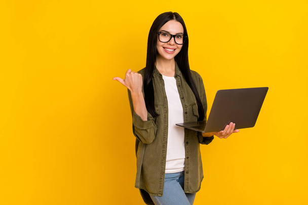 Photo of manager millennial lady hold laptop index promo wear eyewear khaki shirt isolated on yellow background - Foto, Imagen