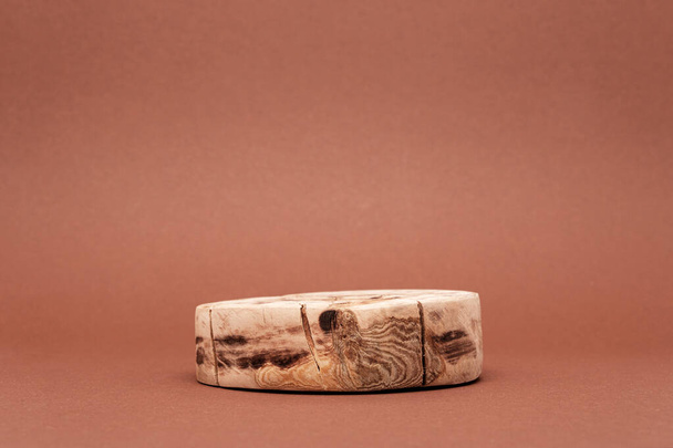 eine runde gesägte Plattform oder Holzpodest zur Präsentation von Öko-Kosmetik auf braunem Hintergrund, leeres Sockelkonzept - Foto, Bild