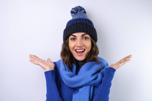 Young woman in a blue golf turtleneck, hat and scarf, on a white background, cheery in a good mood - Photo, Image