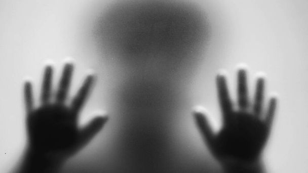 Kind achter het matte glas wazige hand en lichaam zachte focus in monochroom - Foto, afbeelding