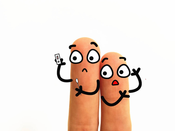 Due dita sono decorate come due persone. Stanno usando il corredo rapido della prova del coronavirus. Uno di loro è risultato positivo. - Foto, immagini