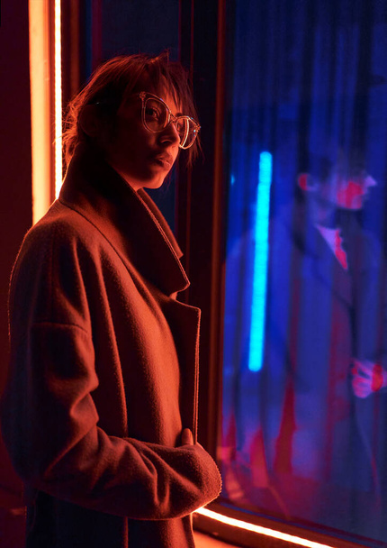 Futuristic cyberpunk style portrait woman in jacket with colored neon ultraviolet lights - 写真・画像