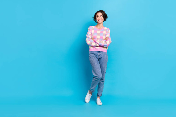 Full body photo of cute young brunette lady crossed arms look empty space wear sweater jeans footwear isolated on blue background - Foto, imagen