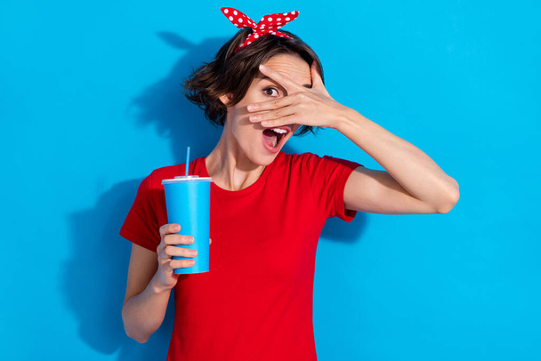 Foto di divertente giovane bruna signora chiudere faccia bere indossare rosso t-shirt cerchietto isolato su sfondo di colore blu - Foto, immagini