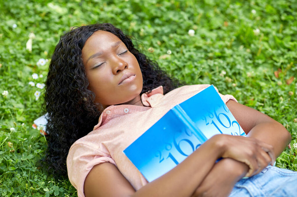 Afrikanisches Studentenmädchen mit Buch schläft im Gras - Foto, Bild