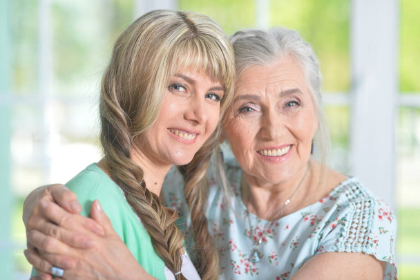 Mature woman embracing with adult daughter at home  - Photo, image
