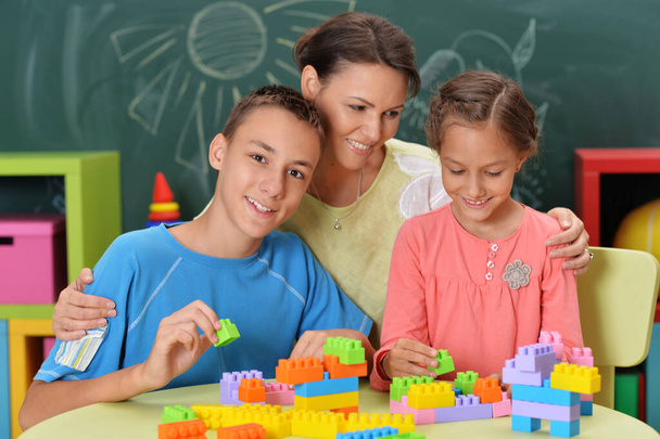 Mother and children  playing with colorful plastic blocks together - 写真・画像