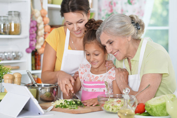 Portrait of happy family coocking salad in kitchen - Zdjęcie, obraz
