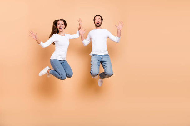 Full length body size view of two attractive cheery partners jumping good mood holiday isolated over beige pastel color background - Photo, Image