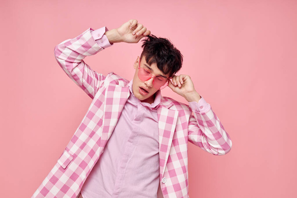 A young man pink glasses checkered jacket fashion posing pink background unaltered - Foto, afbeelding