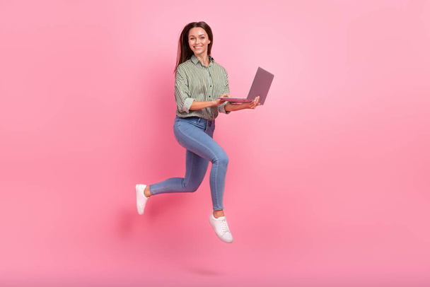 Full body photo of impressed millennial brunette lady run with laptop wear outfit jeans shoes isolated on pink background - Foto, imagen