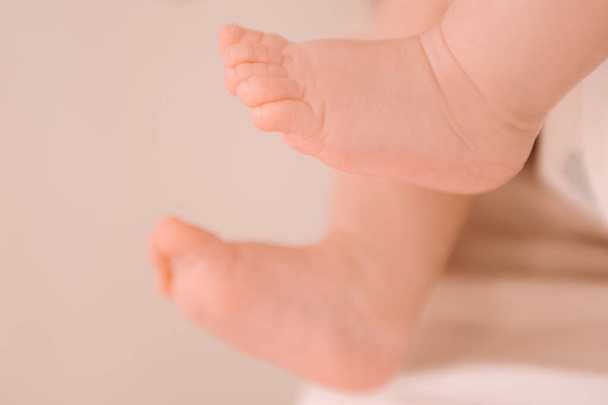 Small legs of a newborn girl on a light background - 写真・画像