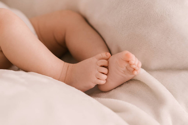 Small legs of a newborn girl on a light background - Foto, imagen