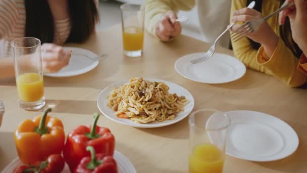 Family lunch. Close up of parents and kids enjoying dinner together at home, sharing plate of spaghetti, tracking shot - Footage, Video