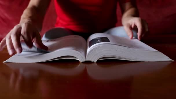 Une personne en chemise rouge consulte la solution dans un livre et la trouve, fond flou, mise au point sélective - Séquence, vidéo
