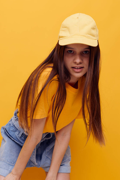 photo pretty woman posing in a yellow T-shirt and cap isolated background - Фото, зображення