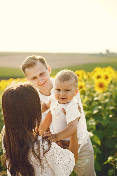 Mother, father and son in white clothes at the sunflowers field - Foto, Imagen