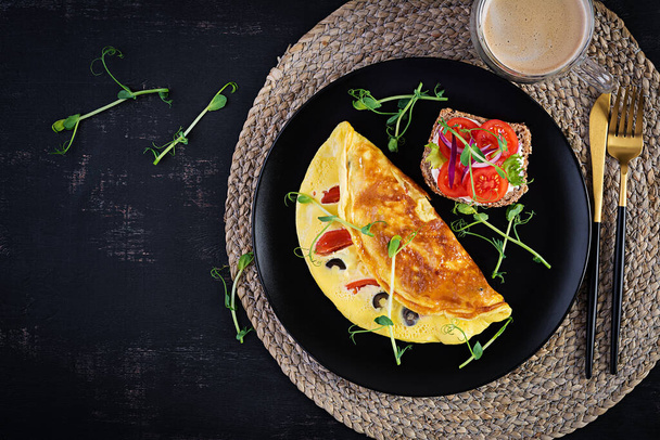 Gezond ontbijt. Omelet met tomaten, kaas en olijven. Sandwich met roomkaas en tomaat. Bovenaanzicht - Foto, afbeelding