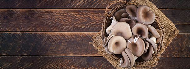 Košík lahodných organických ústřicových hub na dřevěném pozadí. Horní pohled, nápis - Fotografie, Obrázek