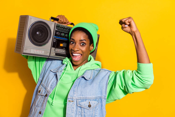 Portrait of delighted crazy person carry tape recorder raise fist isolated on yellow color background - Photo, Image