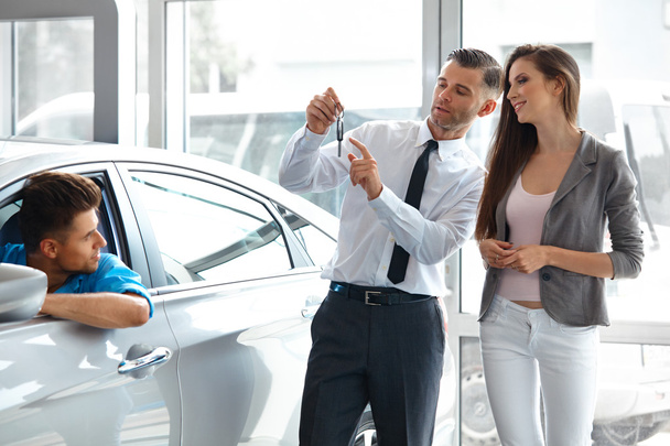 Car Salesman Invites Customers at Showroom. - Zdjęcie, obraz