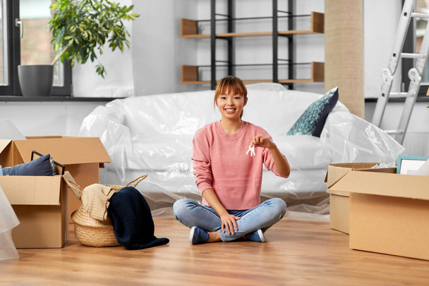 happy woman with house keys and boxes at new home - Foto, imagen
