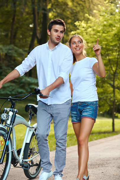 Glückliches Paar mit Fahrrad im Park. - Foto, Bild