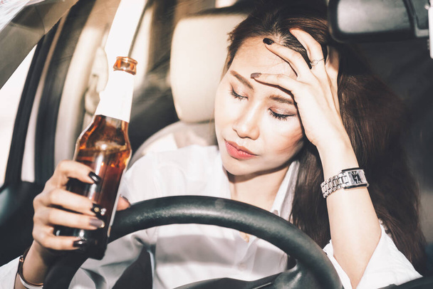 酒を飲んで酔った状態で運転するアジアの女性、運転しながら酒を飲むというコンセプトは、道路上の事故の原因です。. - 写真・画像