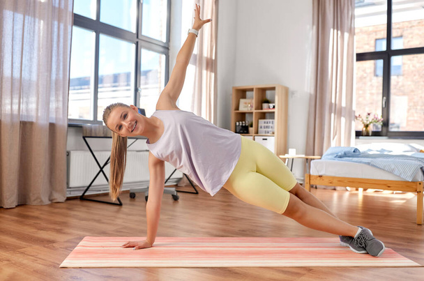 happy teenage girl exercising on yoga mat at home - Φωτογραφία, εικόνα