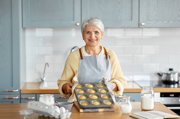 woman with cupcakes in baking mold on kitchen - Fotoğraf, Görsel