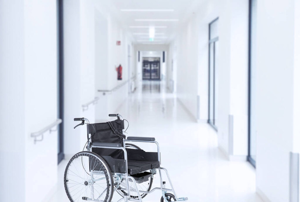 Empty wheelchair in modern hospital corridor interior in light colors. Soft blurred background. High quality photo - Fotoğraf, Görsel
