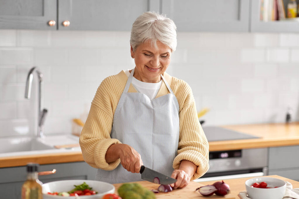 happy woman chopping red onion on kitchen - Φωτογραφία, εικόνα